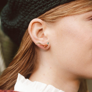 Close-up of a person wearing a pheasant gold plated earring