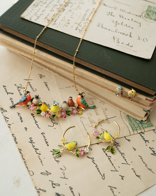 Jewelry set with birds and flowers on a vintage book and paper background